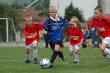 Un bambino avanza con la palla seguito da tre piccoli avversari