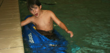 Un ragazzino si tiene al bordo di una piscina.