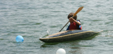 Un bambino in una piccola canoa sta remando sulle acque calme di un lago.