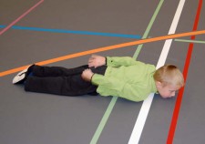 Un bambino sdraiato sulla pancia solleva la testa tenendo le mani dietro la schiena
