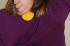 Kind hält einen Flaschendeckel hinter dem Rücken auf Schulterhöhe.