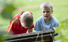 Due bambini consultano una cartina appoggiati ad una panchina