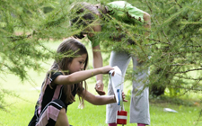 Zwei Mädchen lochen die Karte an einem Posten hinter einem Gebüsch.
