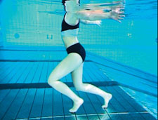 Une femme se déplace dans une eau peu profonde avec les bras tendus de côté.