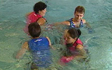 Un groupe de quatre personnes court en cercle dans une eau profonde.