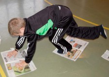 Un enfant place ses mains et ses pieds sur deux feuilles de journal et déplace comme une chenille.