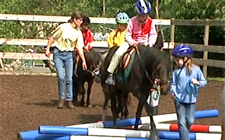 Kinder auf Ponys, die auf den Boden verteilte Hindernisse überwinden