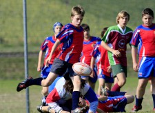Un bambino dà un calcio alla palla da rugby mentre un altro è sdraiato per terra dietro di lui.