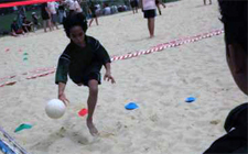 Un bambino sta lanciando una palla su un campo fatto di sabbia.