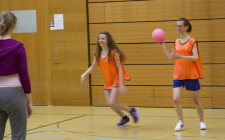 Una ragazza ha una palla in mano e cerca di lanciarla contro un'avversaria.