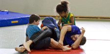Trois enfants luttent sur un tapis.