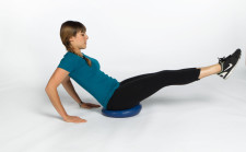 Una ragazza è seduta su un cuscino mobilo tendendo le gambe in avanti. Le mani sono appoggiate al suolo dietro la schiena (braccia leggermente flesse).