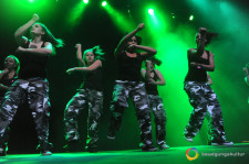 Junge Frauen beim Tanzen auf einer Bühne in grünes Licht eingehüllt.