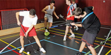 Dei giovani praticano diversi sport contemporaneamente in una piccola area della palestra: calcio, unihockey, ecc.
