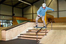 Ein Skater führt einen Backside Boardslide auf einem Downrail durch.