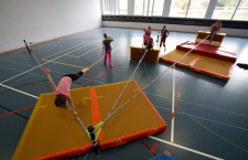 Des enfants dans une salle de sport expérimentent différentes figures sur la slackline.