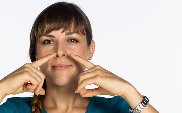 Une jeune femme respire par le nez en appuyant sur les narines avec les doigts.