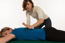 Una donna massaggia con una mano la schiena di un'altra persona sdraiata bocconi