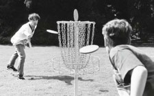 Foto: due giovani lanciano contemporaneamente un frisbee verso lo stesso bersaglio