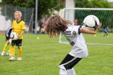 Un enfant rattrape un ballon avec les mains dans le dos.