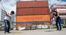 Due giovani ripresi mentre stanno lanciando una pallina contro un container.