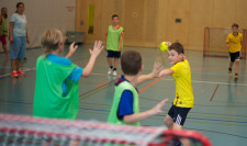 Des enfants jouent au handball dans une salle.
