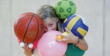 Una bambina è sommersa da numerose palle di forme e dimensioni diverse