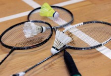 Tre racchette da badminton e tre volani posati per terra in una palestra