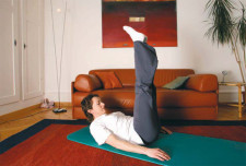 eine Frau auf einer Gymnastikmatte im Wohnzimmer bei einem "Klappmesser".