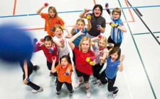 La foto ritrae un gruppo di bambini in una palestra che guardano verso l'obiettivo tenendo delle palline in mano