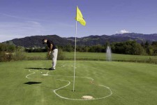 Golfer spielt auf ein Loch auf Minigolf ähnlich gestecktem Parcours.