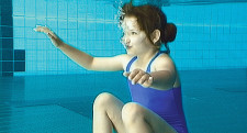 Una bambina è seduta sul fondo di una piscina