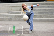 Ein Mädchen wirft einen Ball gegen eine Petflasche.