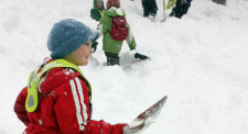 Un bambino nella neve con una pala in mano