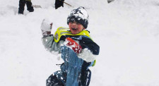 Kind setzt zum Schneeballwurf an.