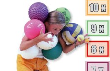 Photo: une fille tient différents ballons en équilibre avec ses bras et sa tête.
