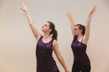 La foto ritrae due ballerine una dietro l'altra con le braccia alzate
