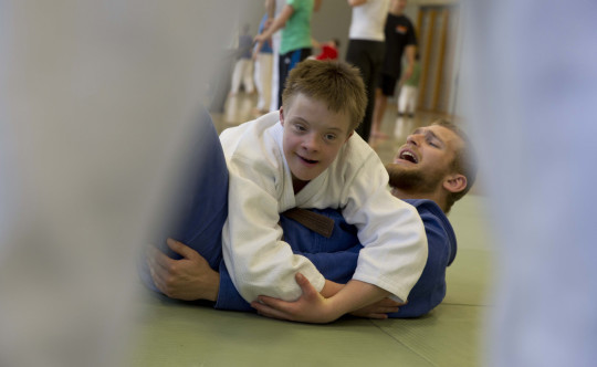 Jugendlicher mit geistiger Behinderung legt beim Judo seinen Lehrer auf den Boden.