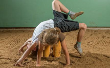 Zwei Kinder bei einer Akrobatikübung im Sägemehl.