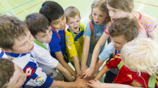 KInder stehen im Kreis und halten je einen Arm in die Mitte des Kreises.