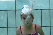 Ein Mädchen atmet unter Wasser aus. 