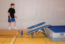 Un enfant est debout sur un banc et s'apprête à sauter sur un mini-trampoline.