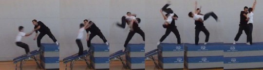 Foto: un allievo esegue un salto mortale all'indietro aiutato da un insegnante 