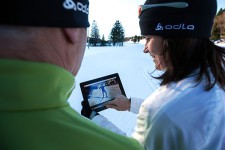 Zwei Skilangläufer schauen auf einem Tablet ein Technik-Video an.