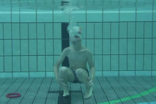 Un garçon est complètement immergé dans une piscine.