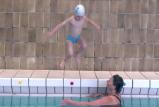 Un garçon saute dans l'eau les pieds en avant.