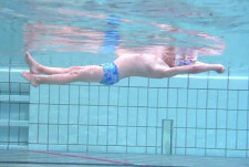 Un bambino scivola nell'acqua in posizione dorsale