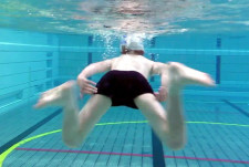 Knabe führt simultane Beinschläge unter Wasser aus.