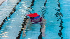 Foto: un bambino nuota sott'acqua mentre sulla superficie galleggia un fiore di gommapiuma