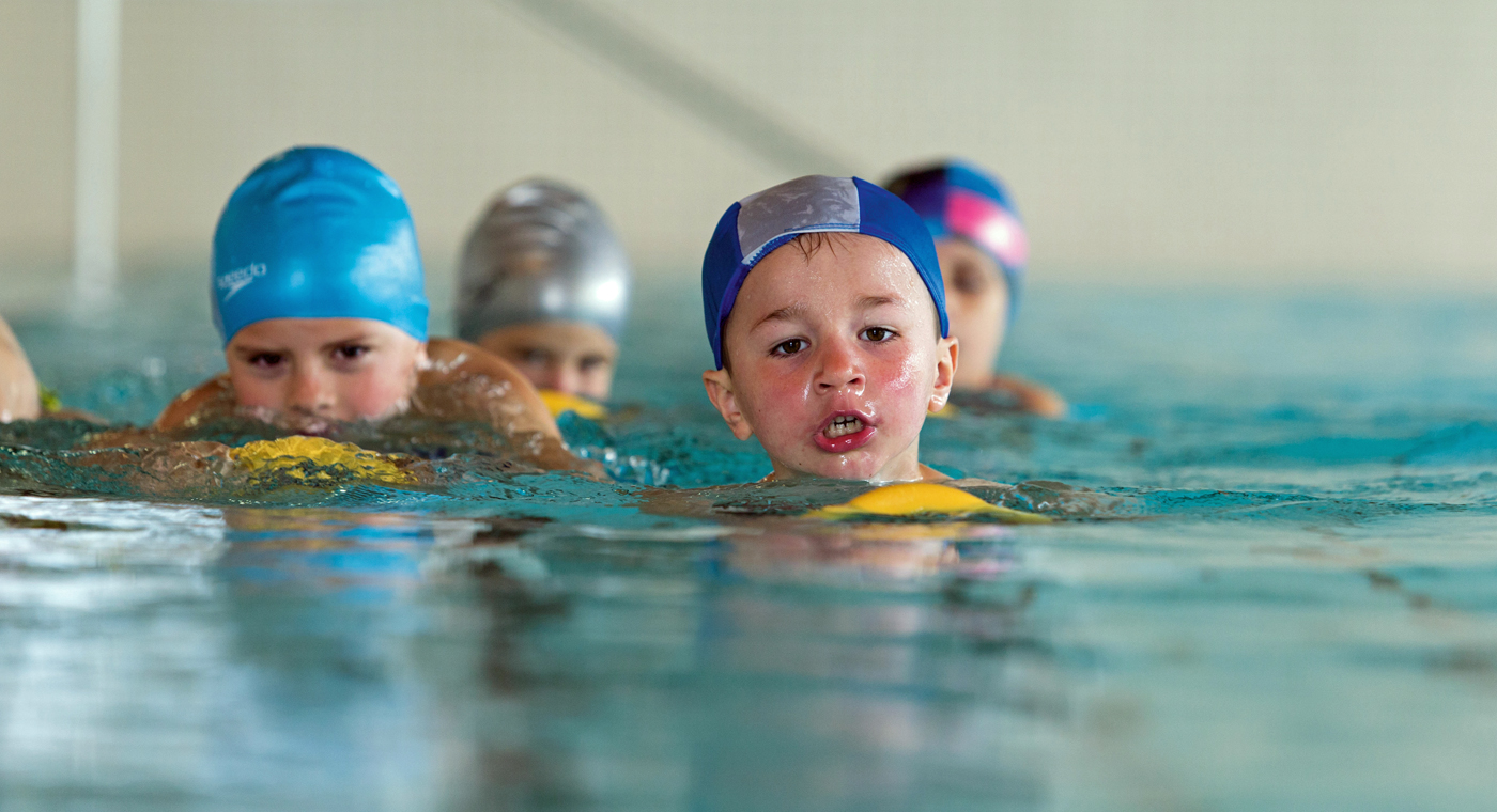 Alcuni bambini mentre nuotano con delle tavolette in una piscina